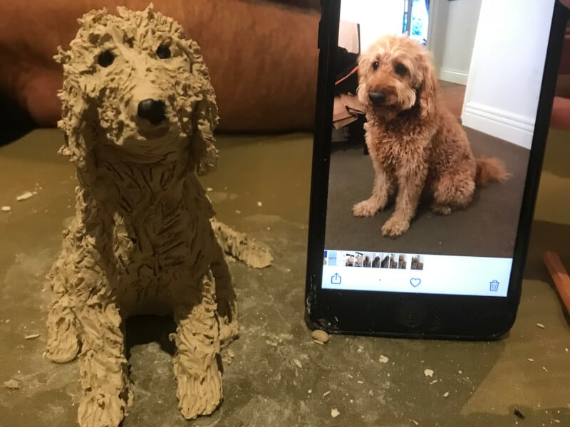 clay dog sculpture beside phone image of dog